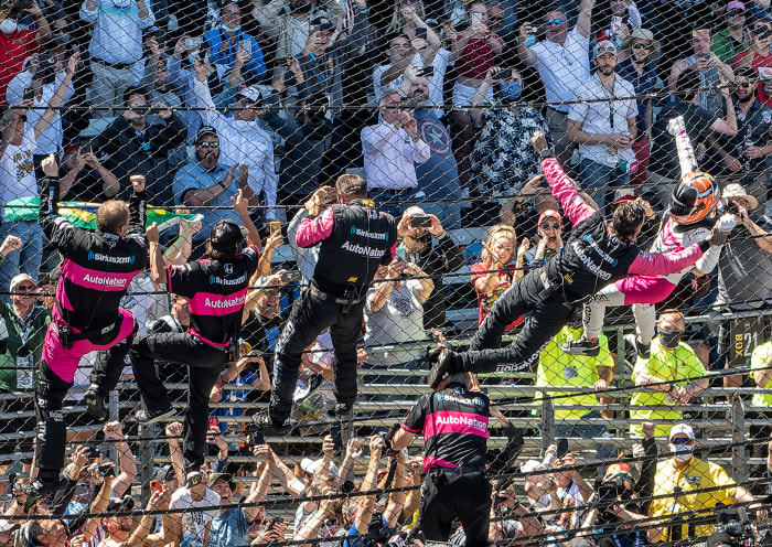 Helio Castroneves celebrates his Indianapolis 500 victory by climbing the fence at Indianapolis Motor Speedway.